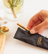 Hand placing gold Frank Green reusable straw into black carry pouch — Adventure Awaits