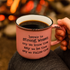 Pink mug with coffee and motivational quote held in front of a fireplace