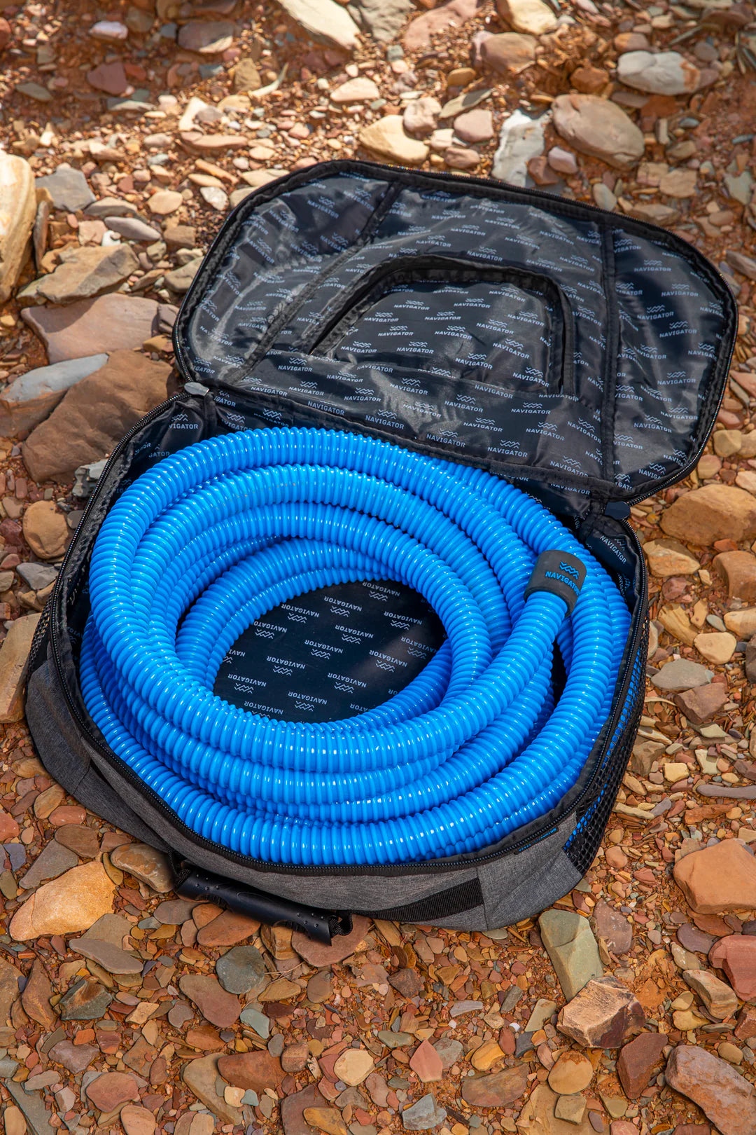 Navigator Sullage Buddy open on gravel with blue sullage hose coiled neatly inside — tidy caravan hose storage — Adventure Awaits