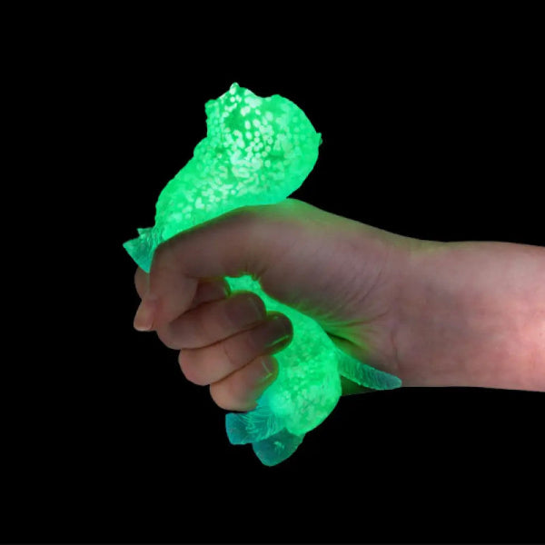 Green glowing object held in a hand against a black background