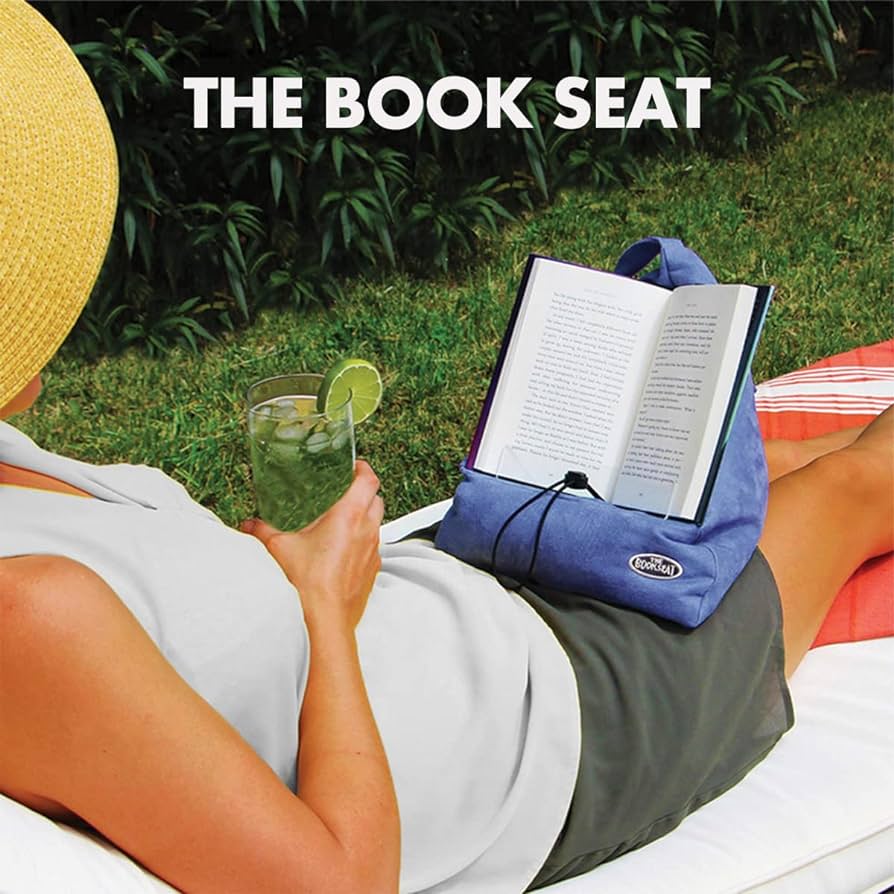 Person relaxing outdoors with The Book Seat holding an open book hands-free — Adventure Awaits