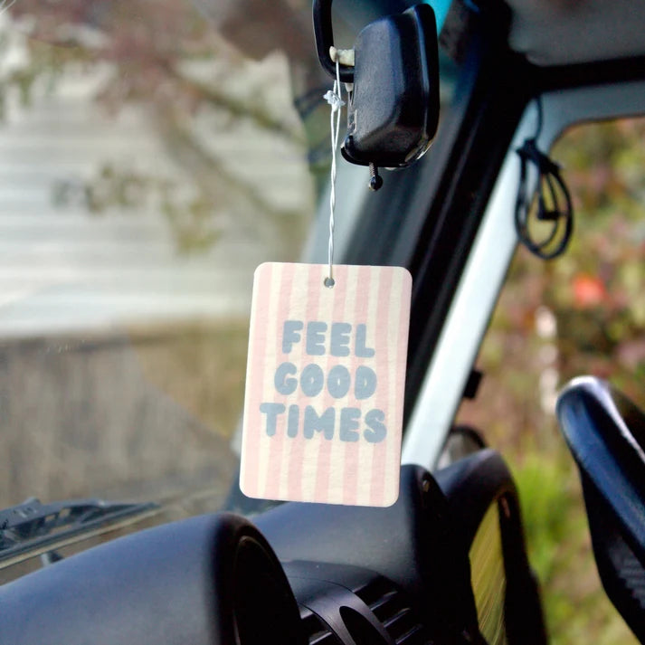 The Commonfolk Feel Good Times boho hanging air freshener on rear view mirror with Mali scent of coconut & lime on a light timber background — Adventure Awaits
