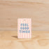 The Commonfolk Feel Good Times boho hanging air freshener with Mali scent of coconut & lime on a light timber background — Adventure Awaits