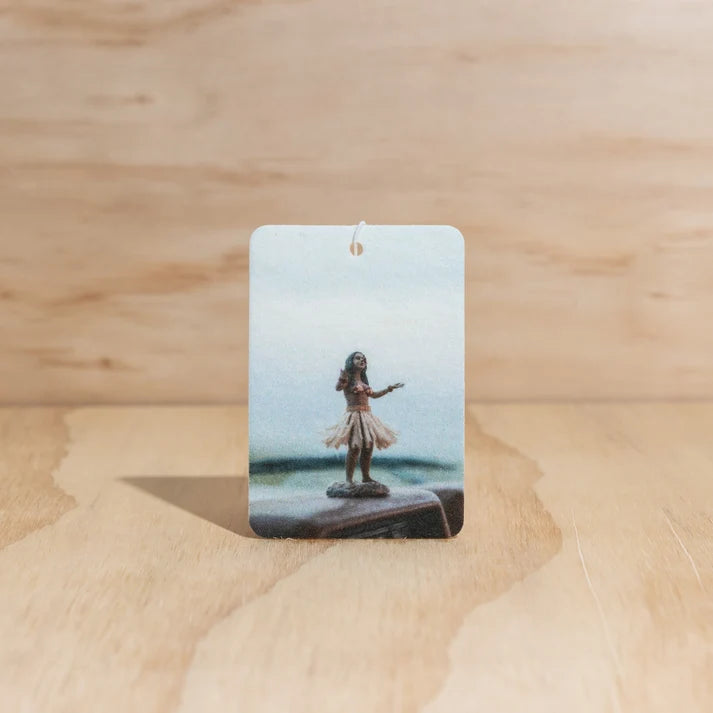 The Commonfolk Hula Girl boho hanging air freshener with Ubud scent of agarwood, musk & patchouli on a light timber background — Adventure Awaits