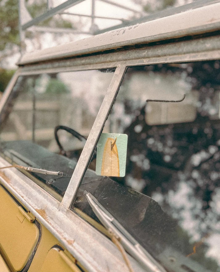 The Commonfolk mustard tail surfboard boho hanging air freshener with Byon Bay scent of almond milk & coconut milk hanging on rear view mirror — Adventure Awaits