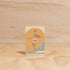 The Commonfolk Surfer Girl boho hanging air freshener with Byron Bay scent of almond milk & coconut milk on a light timber background — Adventure Awaits