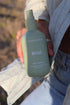 Woman holding The Commonfolk Mist body, linen and room spray in sage green with cucumber mint scent — Adventure Awaits