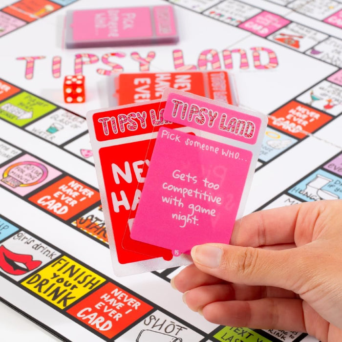 hand holding Tipsy Land game cards over board, including never have I ever and challenge cards, adult party drinking game activity Adventure Awaits