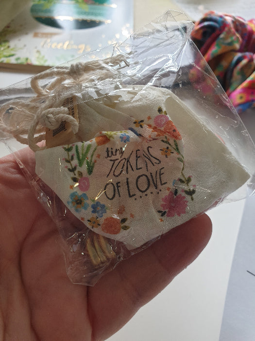 Tiny Tokens of Love drawstring bag in clear packaging held in hand — Adventure Awaits