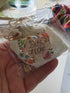 Tiny Tokens of Love drawstring bag in clear packaging held in hand — Adventure Awaits