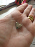 Tiny silver heart Token of Love resting in a hand — Adventure Awaits