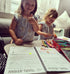 Young children filling in the kids Travel journal with big smiles 