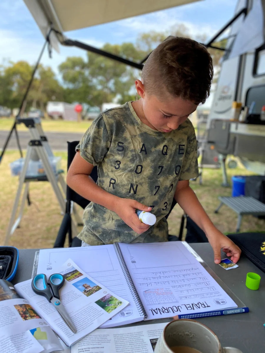 Young boy gluing pictures into the kids travel journal 