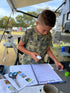 Young boy gluing pictures into the kids travel journal 