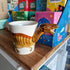 dinosaur ceramic mug featuring a velociraptor design, surrounded by colourful books.