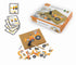 A children's construction vehicle building toy set shown with its retail box, instruction cards, and loose wooden pieces on a white background. The set includes a cork board, orange and yellow vehicle pieces, black wheels, and small wooden connectors.