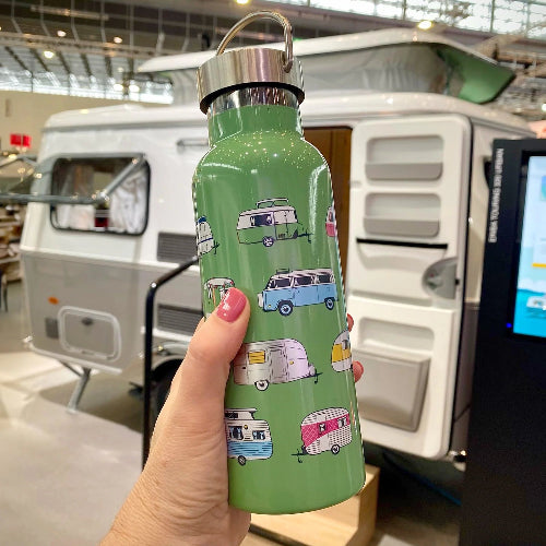 Green water bottle with camper design held in front of a vintage RV.