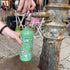 Person filling a green water bottle with a camper design from a public water fountain.