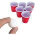 Mini beer pong game with six red cups and a tiny white ball held between fingers — Adventure Awaits
