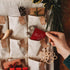 Hand placing a red bake cookies Mindful Advent Activity Card into a fabric advent calendar — Adventure Awaits