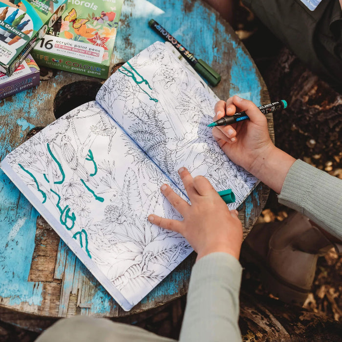 Child colouring detailed nature illustrations in the Wild Activity Book with green brush pens — Adventure Awaits