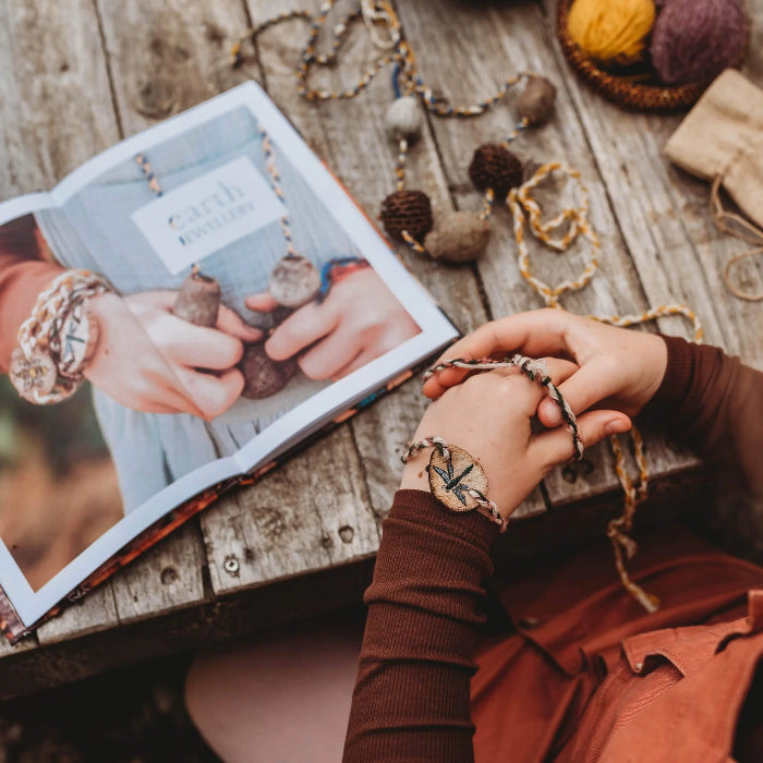 Child making nature jewellery beside an open Wild Child craft book on a rustic table — Adventure Awaits