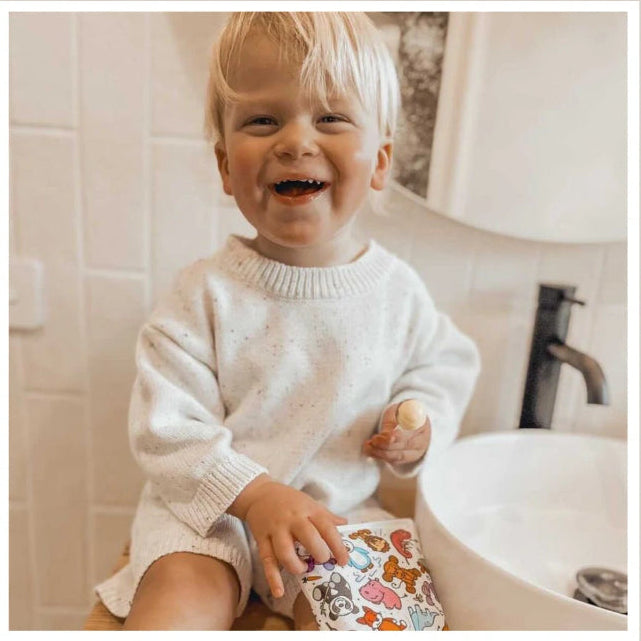 child in bathroom holding animal ouchie pouchie cold pack on knee - Adventure Awaits