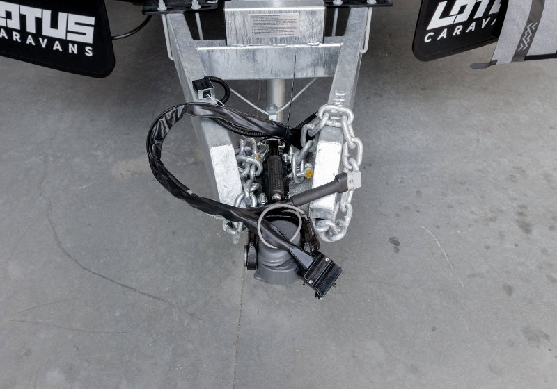 Exposed caravan tow hitch with chains and trailer wiring before trailer plug cover is fitted — Adventure Awaits