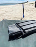 Navigator grey caravan storage bag folded on beach mat beside sand and shovel — Adventure Awaits