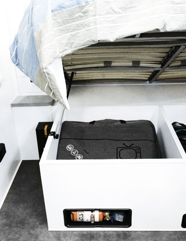Grey padded caravan TV storage bag tucked under caravan bed — Adventure Awaits