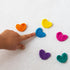 Hand pointing to colourful crocheted heart tokens for Ouchie Pouchie reward activities — Adventure Awaits