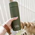 Khaki Frank Green bottle with flip lid held outdoors beside a dog — Adventure Awaits