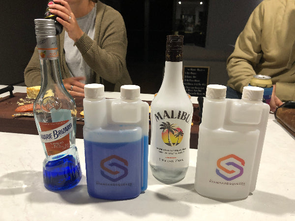 Blue liqueur and Malibu bottles beside two Standard Squeeze Bottles on a home bar — Adventure Awaits