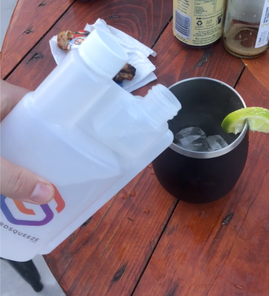 Standard Squeeze Bottle pouring a drink into an ice-filled cup with lime on an outdoor table — Adventure Awaits