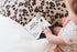Baby touching Ten Little Kisses For You board book on bed with leopard cushion — Adventure Awaits