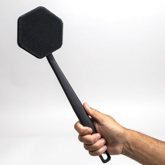 man's hand holding up tooletries back scrubber against white background