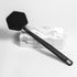 black tooletries back scrubber shown propped on marble block on white background
