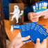 Players hold blue caption cards while playing What Do You Meme? Family Edition at a table — Adventure Awaits
